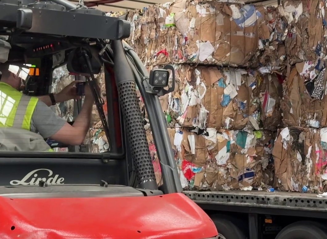 Forklift driver checking a delivery of recovered paper bales on the truck with a tablet